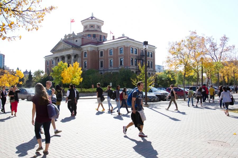 Students walking outdoors in varying directions in front of the administration building.