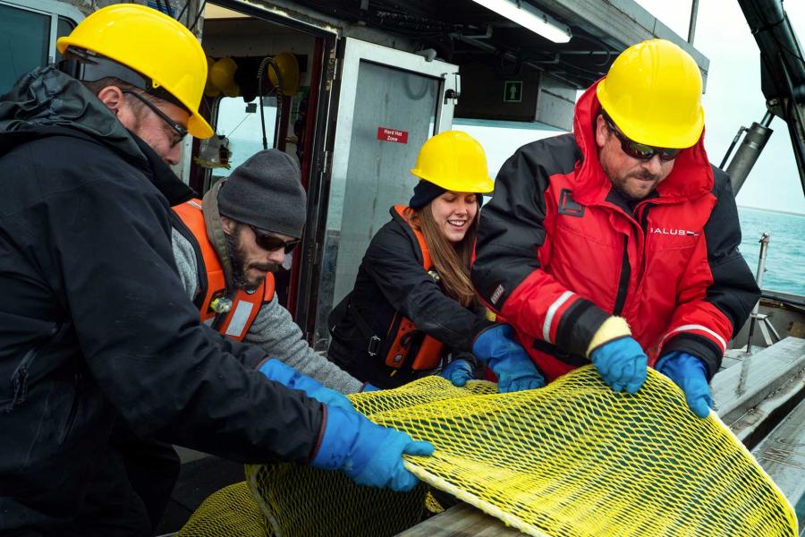 Four researchers holding a net aboard the William Kennedy.