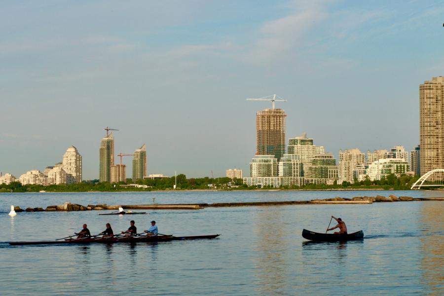 A kayaker and some people in a canoe in the water of toronto harbour.