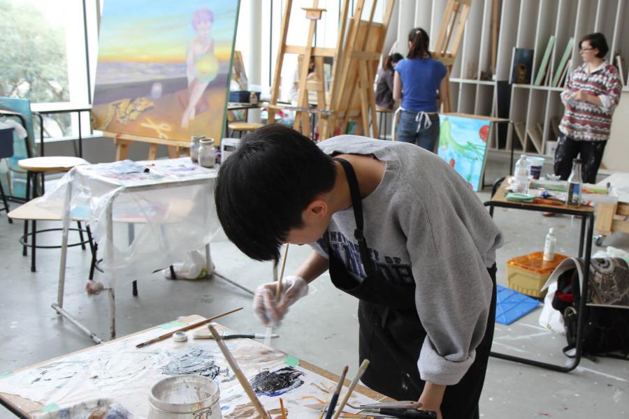 Students paint in a brightly lit studio.