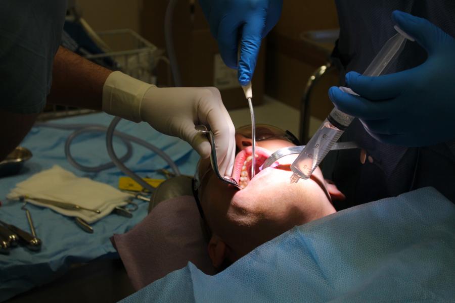 Two pairs of hands carefully work on a patients mouth.
