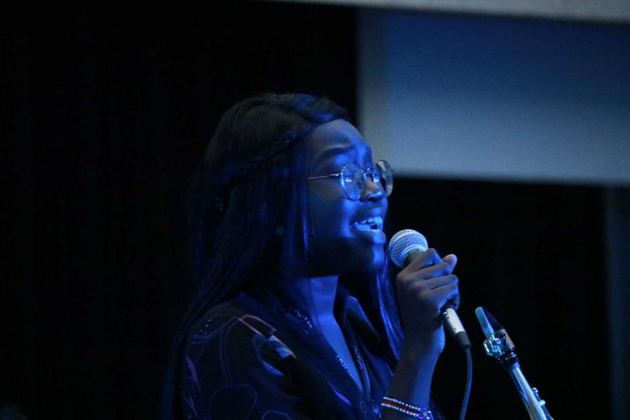 Performer Jasmine Henry sings into a microphone in concert.