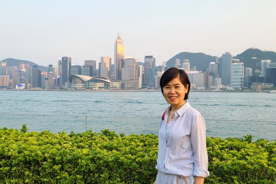 Mei Yin Chan, an East Asian woman standing outdoors in front ocean fronted cityscape