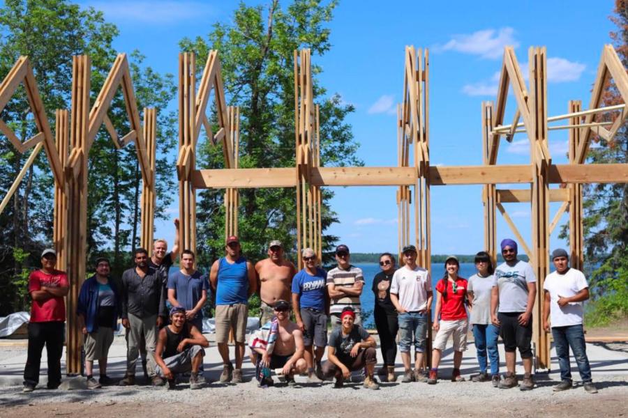 Members of the Engineering and Architecture faculties stand together in front of a ceremonial structure they have built at Shoal Lake 40. 