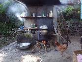 Outdoor kitchen with locally constructed water tank. On the fire is a still for making local brew