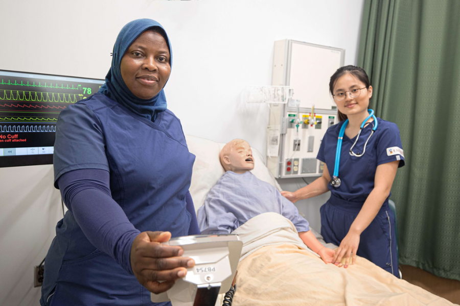 Two nursing students work with a manikin.