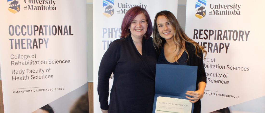 An occupational therapy student stands for a photo with her award.