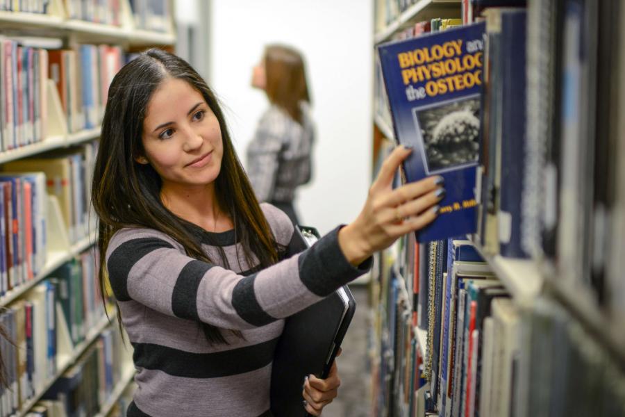 Student chooses a book from the library shelves