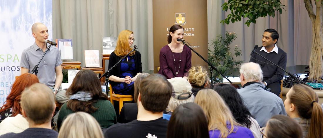 Four Cafe Scientifique panelists sit side by side on stage talking to a crowd of attendees.