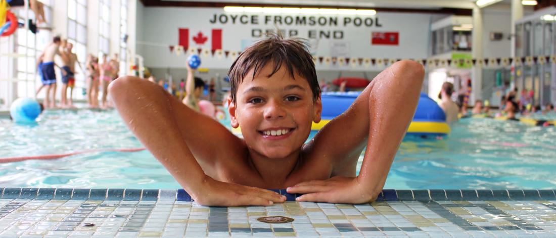 A young swimmer gets set to hoist himself out of the shallow end of the University pool. 