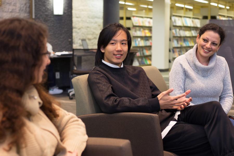Three people sitting in a University of Manitoba Library having a conversation.