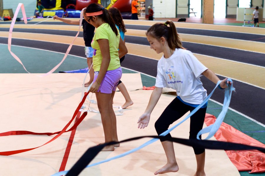 A group of kids playing with colourful rhythmic gymnastics ribbons.