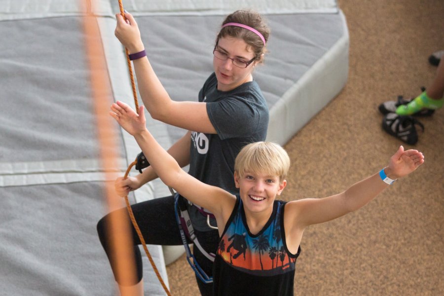 An excited child gets ready to climb the climbing wall.