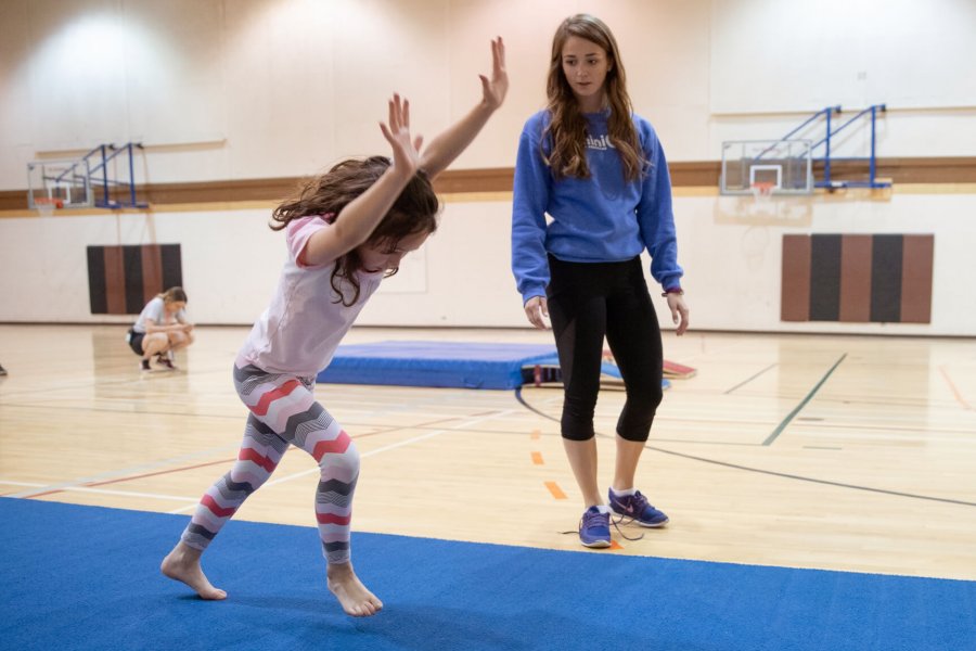 A Mini U leader watches a participant doing a cartwheel.