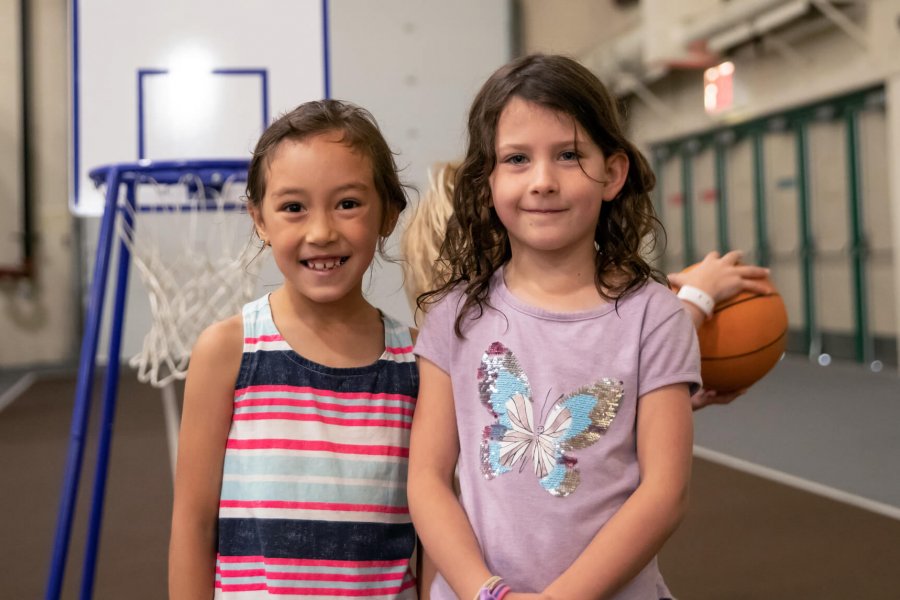 Mini U kids stand in front of a basketball net.