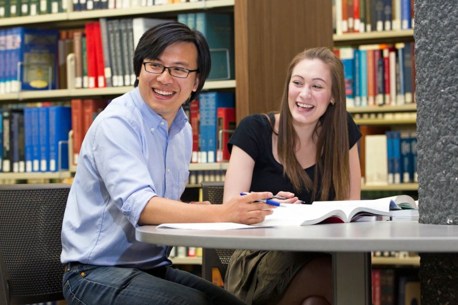 A student and tutor happily work together in a library.
