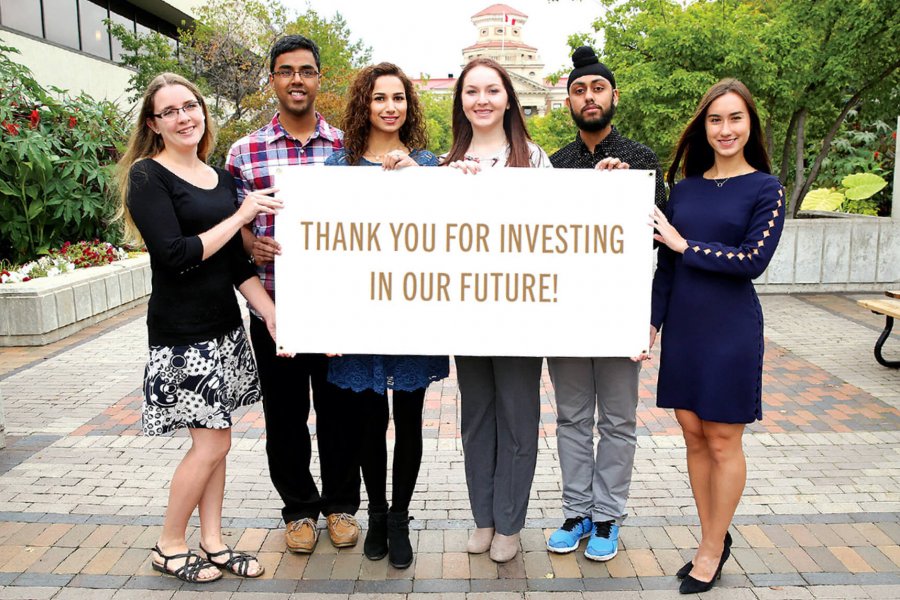 Six students stand together holding a sign that says thank you for investing in our future.