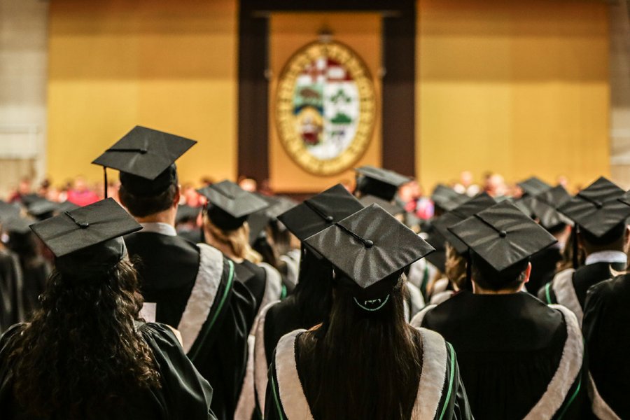 Students in graduation gowns and caps wait at convocation.