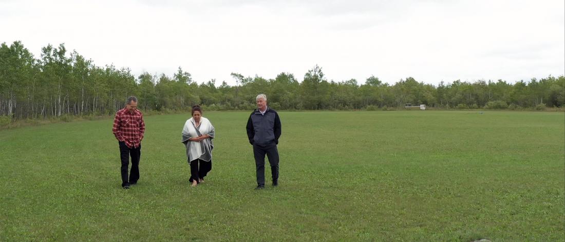 EJ Fontaine, Ardell Cochrane and Robert Maytwayashing walk through a field.
