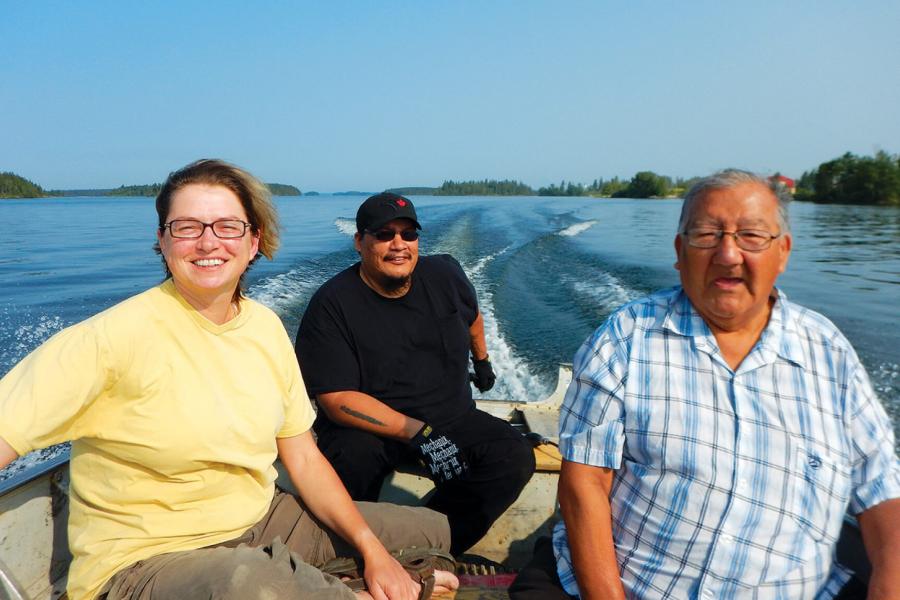 Three people in a boat on a lake. 