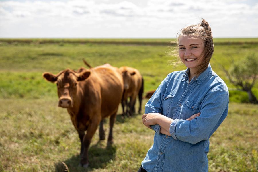 Female student in field with cattle.