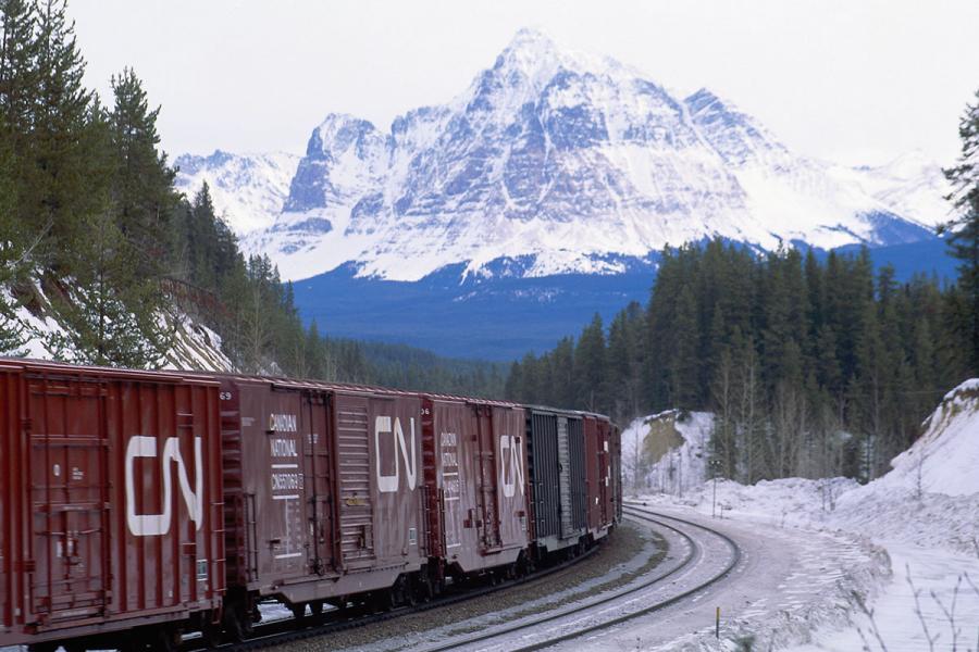 Rail cars move along the track under a mountain