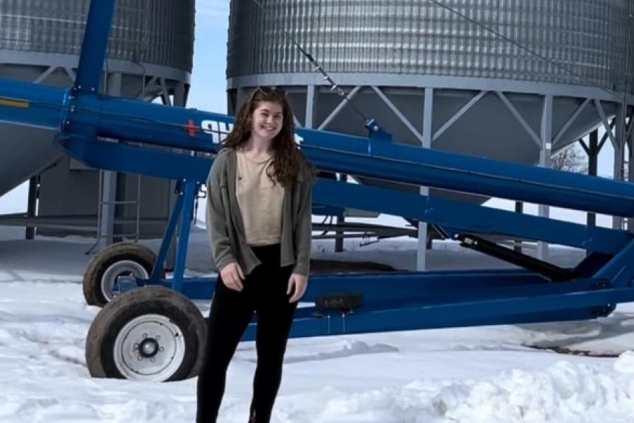 A picture of Jess Goodwin in front of grain bins
