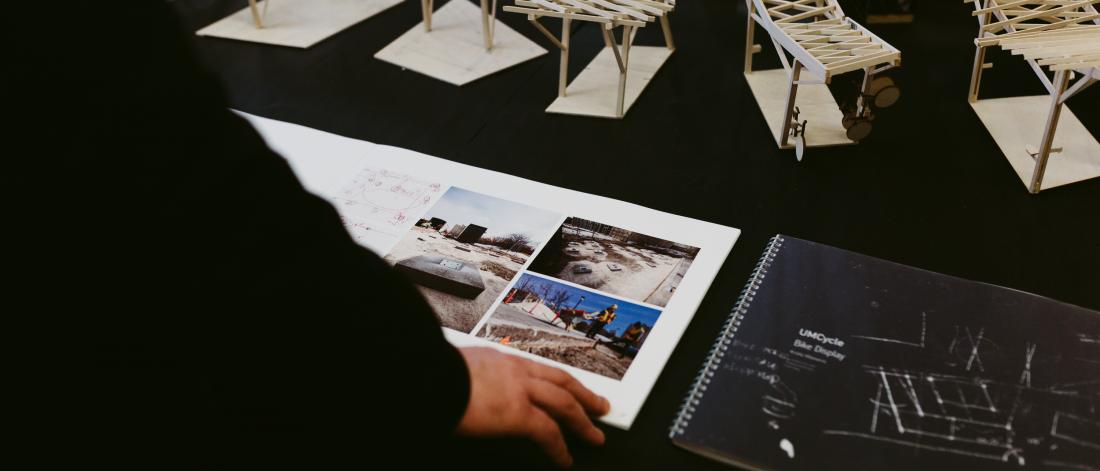 person flipping through a portfolio with wooden models in the background