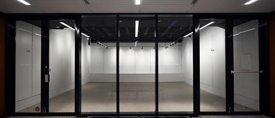 empty gallery space with white walls, terrazo floor and track lighting