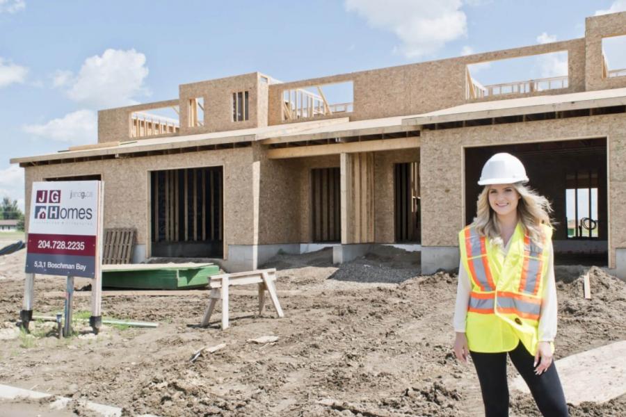 An architecture student stands in front of a partially built home for J and G homes where she is participating in a co-operative integrated work program.