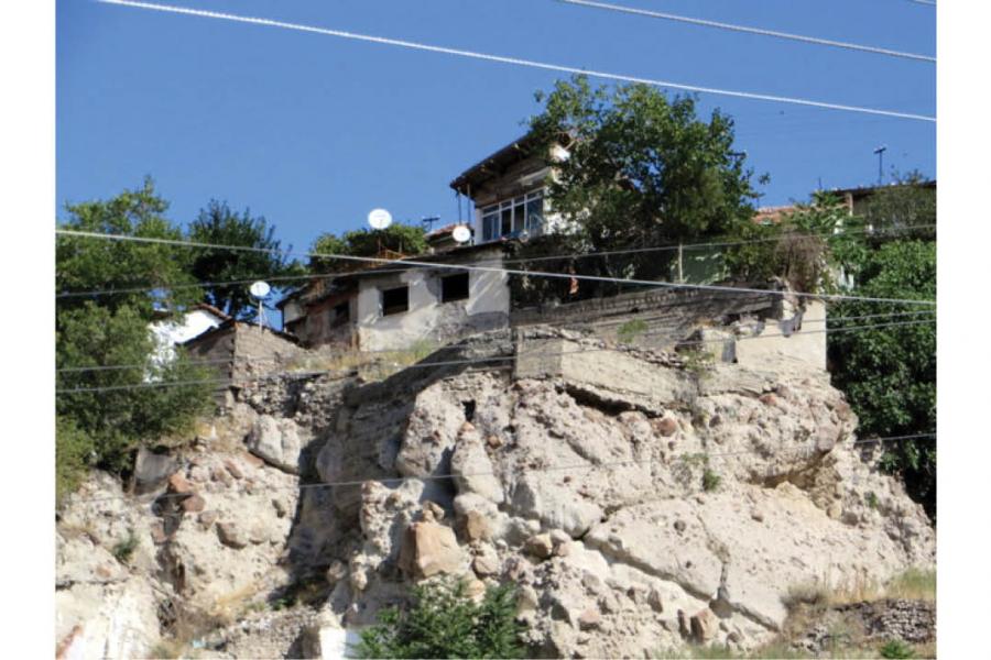 house built on a rock on the side of the mountain