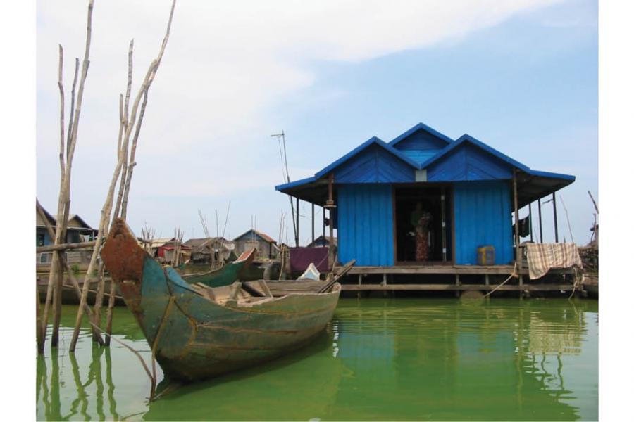 canoe in water in front of a small blue house