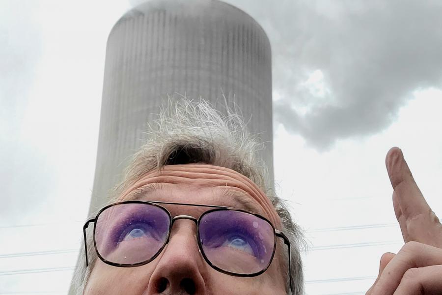 man looking up at chimney with dark smoking emerging