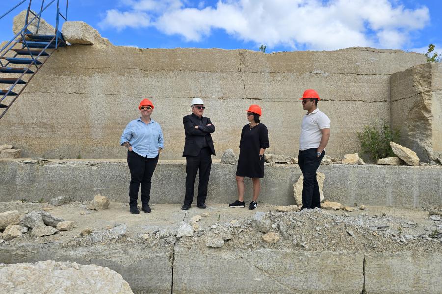 Four individuals wearing construction hats in a quarry.