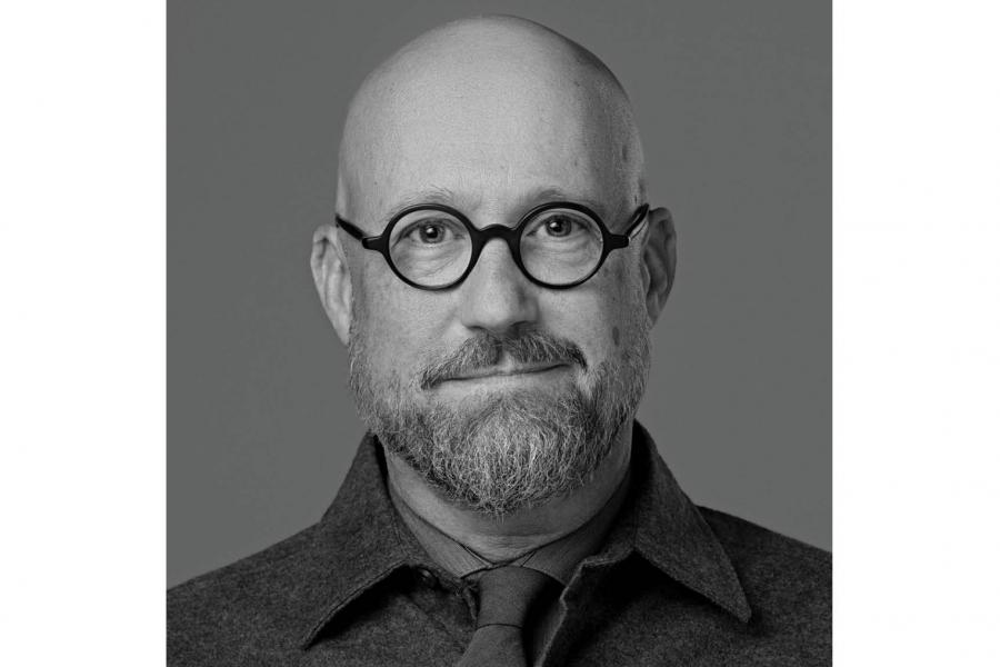 Black-and-white portrait of a bald man with glasses and a beard.