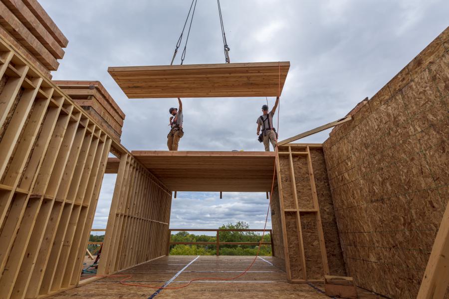 Construction workers aligning a wooden panel on a building site.
