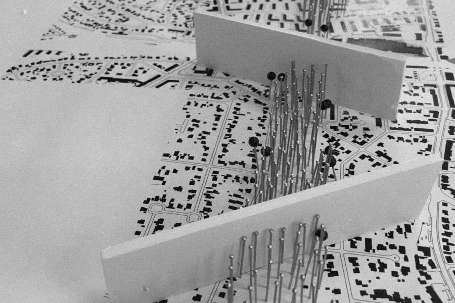 Architectural model on a detailed urban map with white panels and thin rods.