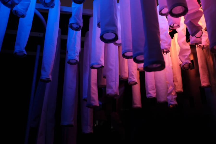 Fabric tubes hanging vertically, illuminated by blue to pink lighting gradient.