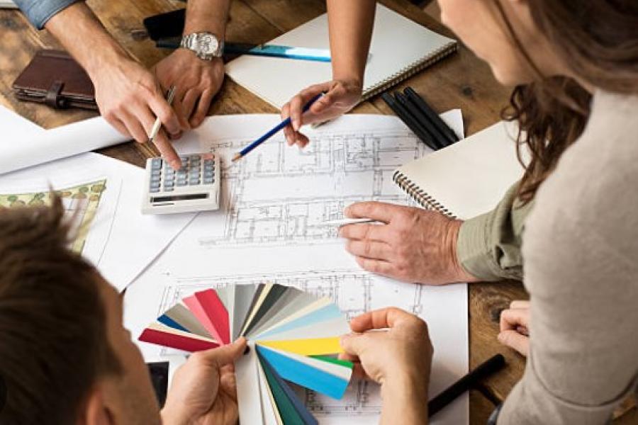 A group discussing architectural blueprints, using a calculator and color swatches.