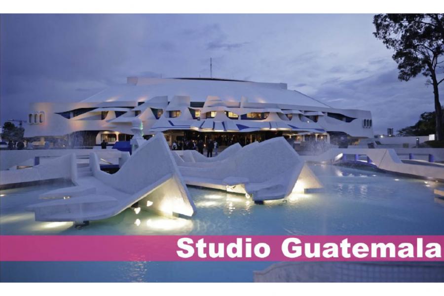 Futuristic white building with angular shapes and a glowing fountain in front under a dusky sky. Text overlay reads "Studio Guatemala."