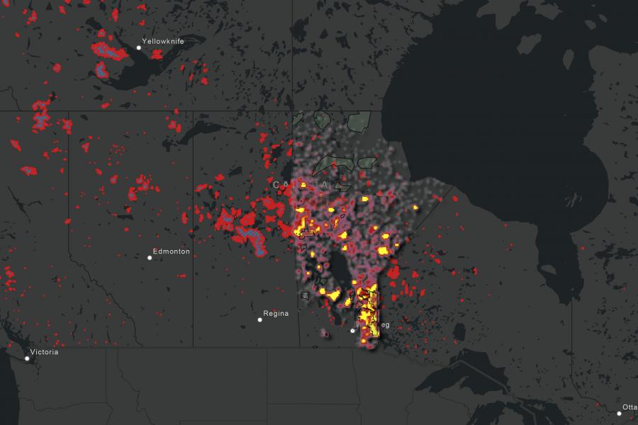 Map of Canada highlighting wildfire activity. Red, yellow, and orange areas indicate high intensity near cities like Winnipeg and Regina on a dark background.