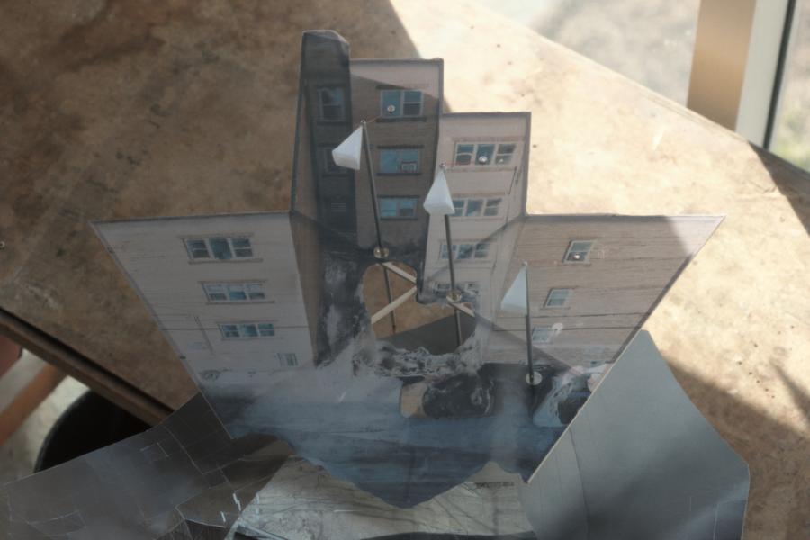 Abstract collage with a paper sculpture of an inverted building featuring white street light lamps.