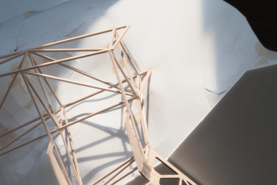 Abstract design with wooden geometric structure casting complex shadows on a textured, light-colored wall.
