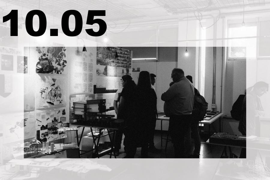 Black-and-white art exhibition in a studio, where visitors view collages and prints amid tables, hanging lights, and industrial fixtures.