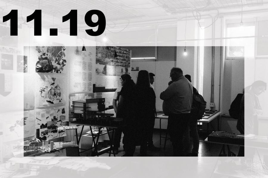 Black-and-white art exhibition in a studio, where visitors view collages and prints amid tables, hanging lights, and industrial fixtures.