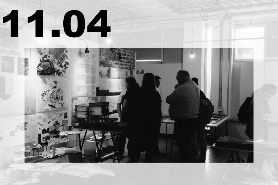 Black-and-white gallery scene with visitors viewing artworks and display tables.