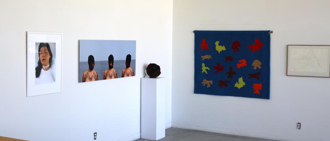 A collection of Indigenous Art paintings and sculpture, displayed in a white walled studio