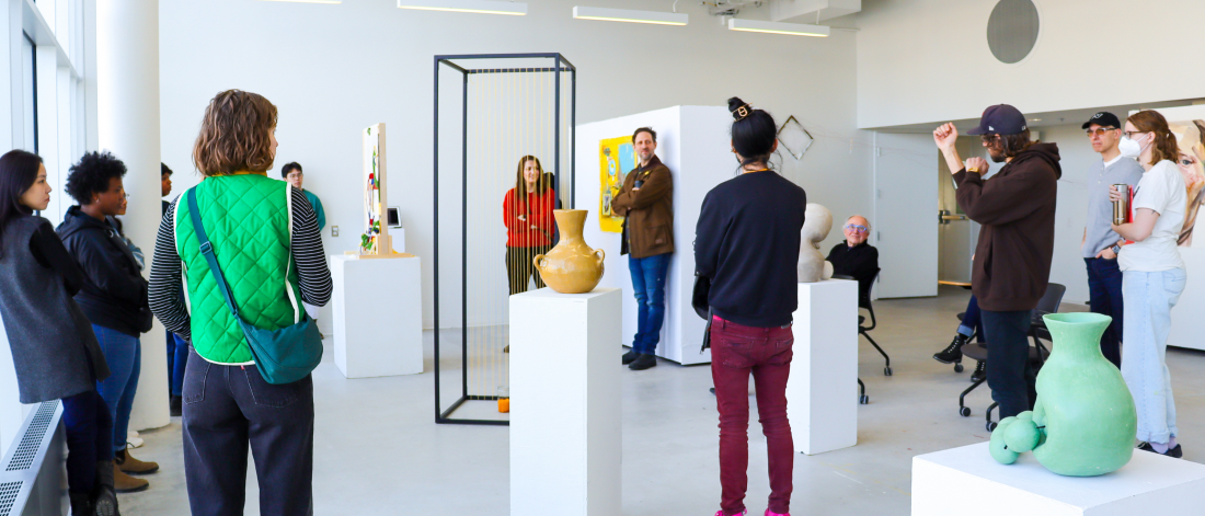 Students gather around the ceramics works in discussion