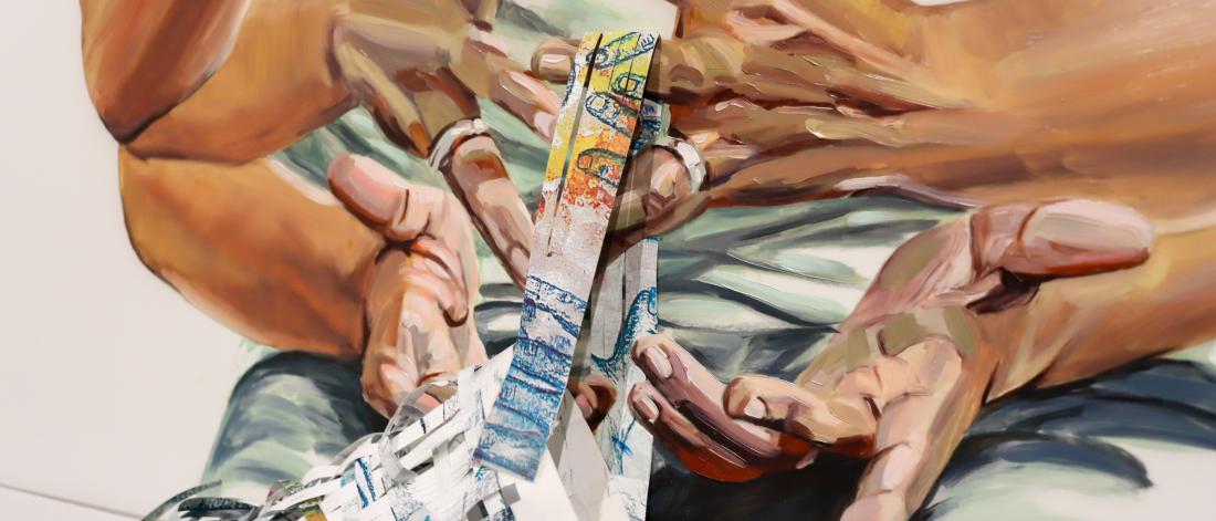 Close-up of painted hands holding and pulling strips of woven paper cascading from the artwork.