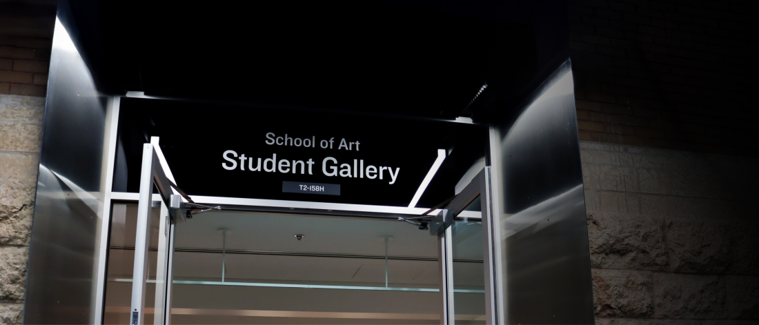 Entrance to the School of Art Student Gallery at the University of Manitoba, viewed through open glass doors.